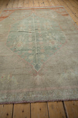 Distressed vintage Oushak rug texture: sun-faded sea foam green pile, delicate germinating vine.