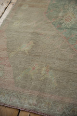 Vintage distressed Oushak rug's short pile texture, sun-faded sea foam green and sand.