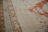 Meandering vine palmette border detail on a distressed Oushak carpet with abrashed field.