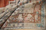 Folded vintage distressed Oushak showing sand field, chestnut border, blush and turquoise palmette detail.