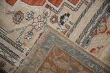 Abrashed sand field with pink floral motifs on vintage Oushak, revealing a turquoise and chestnut border.
