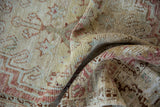 Textured distressed pile of vintage Oushak runner, showing faded rose and pale saffron tones.