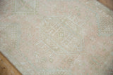 Distressed texture of vintage Karaja runner with pale pink, ivory, and faint green geometric motifs.