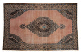Vintage distressed Oushak carpet with a serrated medallion on a dusty blush field in brown and blue.