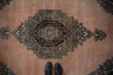 Serrated medallion in brown and blue on a distressed Oushak carpet with an abrashed dusty blush field.