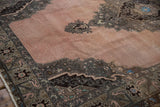 Angled view of the distressed Oushak's low pile, showing the serrated medallion on a dusty rose field.