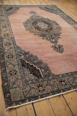 The serrated medallion and worn texture of a vintage Turkish Oushak carpet, viewed from an angle.