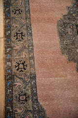 Even wear on the distressed dusty rose pile and detailed brown border of a vintage Oushak carpet.