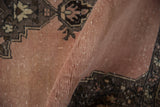 Textured pile of a distressed Oushak carpet in dusty blush with faint foundation showing.