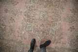 Distressed vintage Tabriz carpet with pale pink, dusty mauve floral patterns and worn texture.