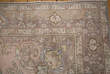 Distressed vintage Tabriz corner showing faded mauve, pink, and blue arabesque patterns.