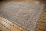 Distressed Tabriz carpet corner detail featuring pale pink, slate blue, and arabesque vine motifs.