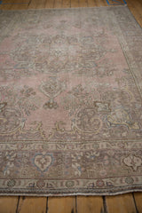 Distressed pale pink field and dusty mauve, slate blue floral motifs within the ornate border.