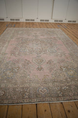 Distressed vintage Tabriz carpet showing faded pink, mauve, and blue-gray floral scrollwork.