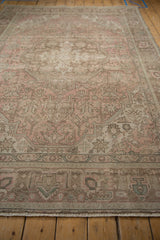 Distressed vintage Tabriz rug showing faded rose pink blossoms, brown vinery, and soft pale green details.