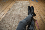Distressed Oushak runner with low pile and worn texture showing geometric floral design.