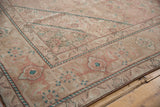 Distressed Tabriz carpet corner featuring faded Herati motifs in beige, rose, and jade green.