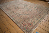 Distressed Tabriz carpet corner shows faded beige, rose, green Herati motifs and fringe.