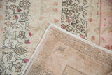 Folded Sivas rug corner shows distressed ivory-blush vinery, faint foundation, and hand knotted back.