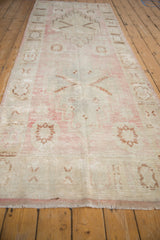 Decorative distressed Oushak runner with faded pink, ivory, and brown floral patterns.
