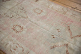 Distressed Oushak rug pile revealing faded pink, beige, and brown tones with evident wear.