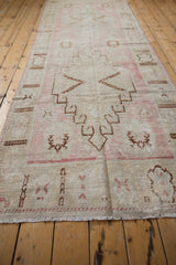 Distressed Oushak runner: worn beige pile, faded pink and brown geometric motifs, intact fringe.