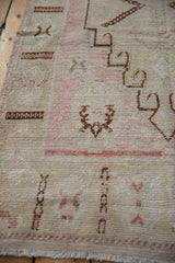 Distressed vintage Oushak runner, showing textured pile with faded pink and brown motifs.