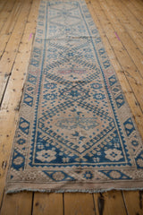 Lengthwise perspective of a vintage Melas runner with faded blue and sand geometric medallions.