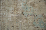 Distressed pile of a vintage Persian Tabriz carpet, showcasing worn ivory and soft blue millefleur details.