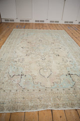 Faded ivory, pale blue distressed Tabriz carpet with floral motifs and fringe.