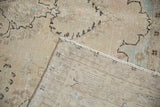 Distressed vintage Tabriz carpet pile in ivory and beige, revealing its woven foundation.