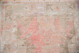 Distressed Oushak rug texture with worn pink, ivory, and beige pile showing foundation.