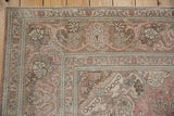 Vintage distressed Tabriz carpet corner: scrolling arabesques, trefoil florals, dusty rose, pale green tones.