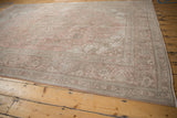 Intricate faded dusty rose and pale coffee brown floral vinery on distressed vintage Tabriz carpet.