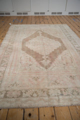Distressed vintage Oushak rug surface with nuanced pale pink and coffee brown medallion.