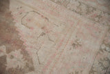 Detail of distressed Oushak pile, showing pale coffee, pink, and exposed foundation knots.