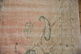 Distressed Oushak carpet pile with abrashed dusty rose, cream, and jade green floral motifs.