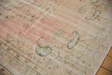 Distressed vintage Oushak rug with faded dusty rose, green floral motifs, and texture from wear.