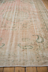 Distressed Oushak rug with faded green vinery on a low-pile dusty rose field.