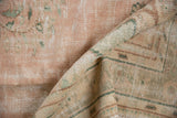 Rolled vintage distressed Oushak carpet, soft pile revealing time-softened dusty rose and green vinery.