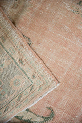 Close-up of the distressed pile texture in dusty rose and the woven foundation pattern.