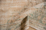 Distressed vintage Oushak carpet pile texture, showing wear to foundation in apricot and green.