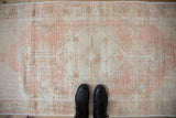 Distressed vintage Oushak rug texture with worn pink and ivory pile showing foundation.