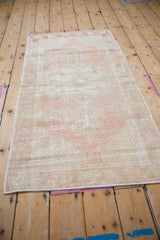 Distressed vintage Oushak rug texture with visible low pile, faded pink, and beige tones.