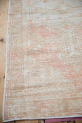 Vintage distressed Oushak rug with low pile texture showing foundation and soft pink, ivory tones.