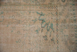 Detail of distressed vintage Oushak rug's pale peach and dusty sage green patterns.