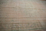 Worn pile of a distressed Oushak rug with pale rose, ivory, and faint mint motifs.