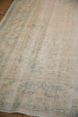 Worn texture of a vintage Oushak rug, highlighting faded peach and pale mint patterns.