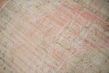 Storied texture of a distressed vintage Oushak rug with softened pink and green hues.