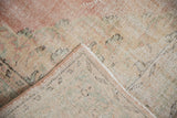 Distressed Oushak rug corner revealing hand-knotted reverse, secured selvage, and soft colors.
